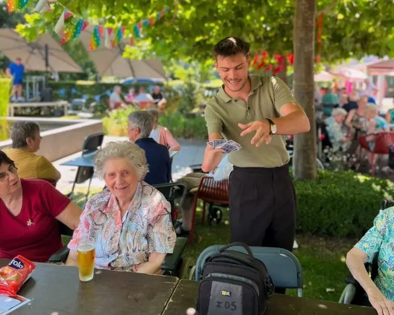 Een gast lacht tijdens close-up magie op een familiefeest