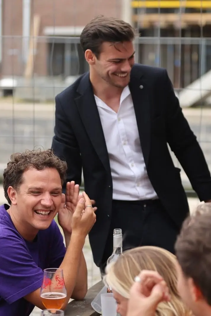 Wout staat glimlachend tussen gasten op een evenement