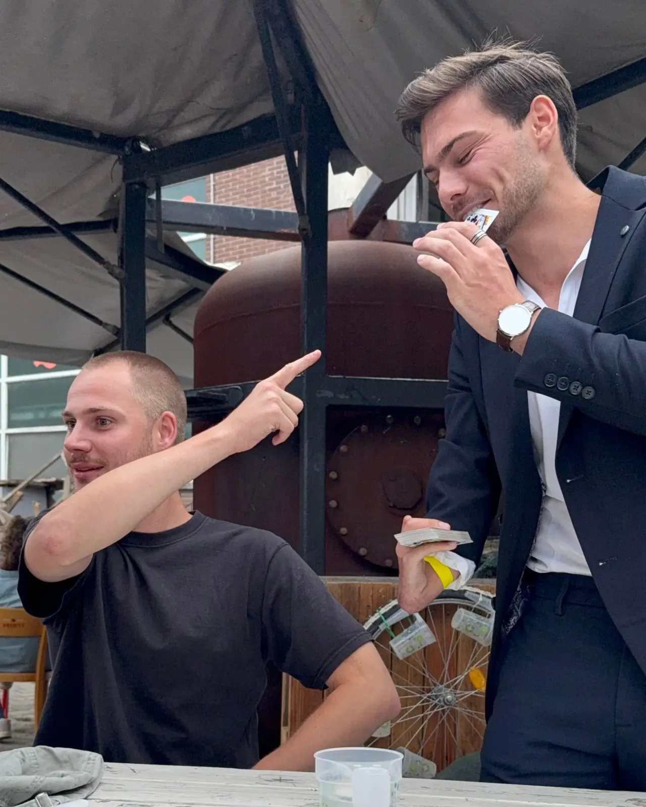 Een toeschouwer reageert verbaasd op een kaarttruc tijdens een buitenevent