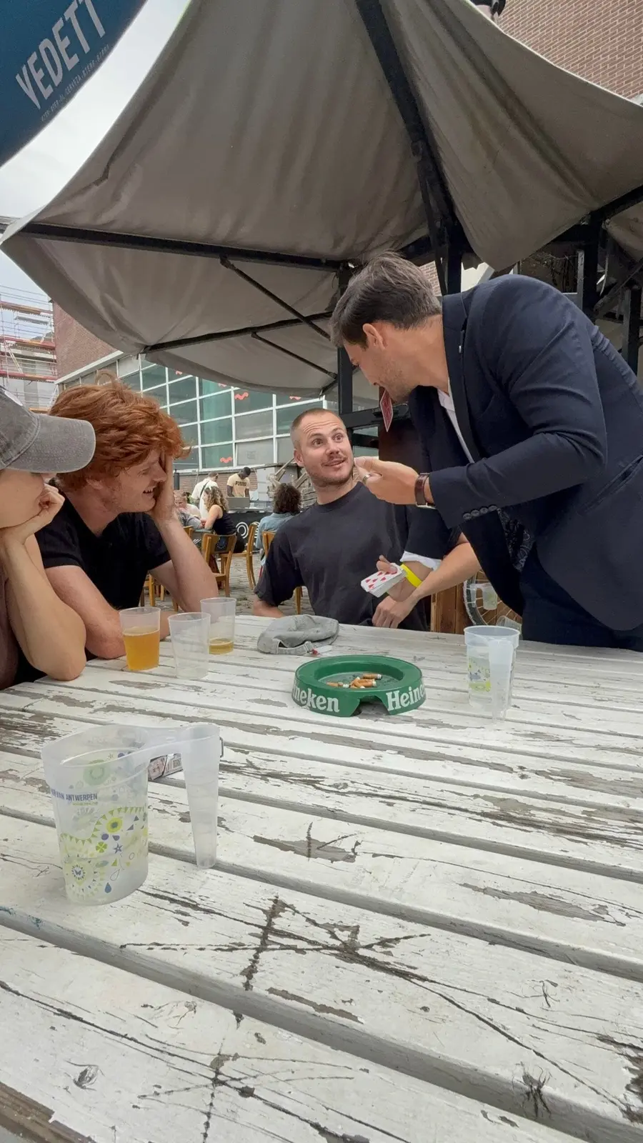 Vrienden kijken aandachtig toe bij een kaarttruc aan tafel